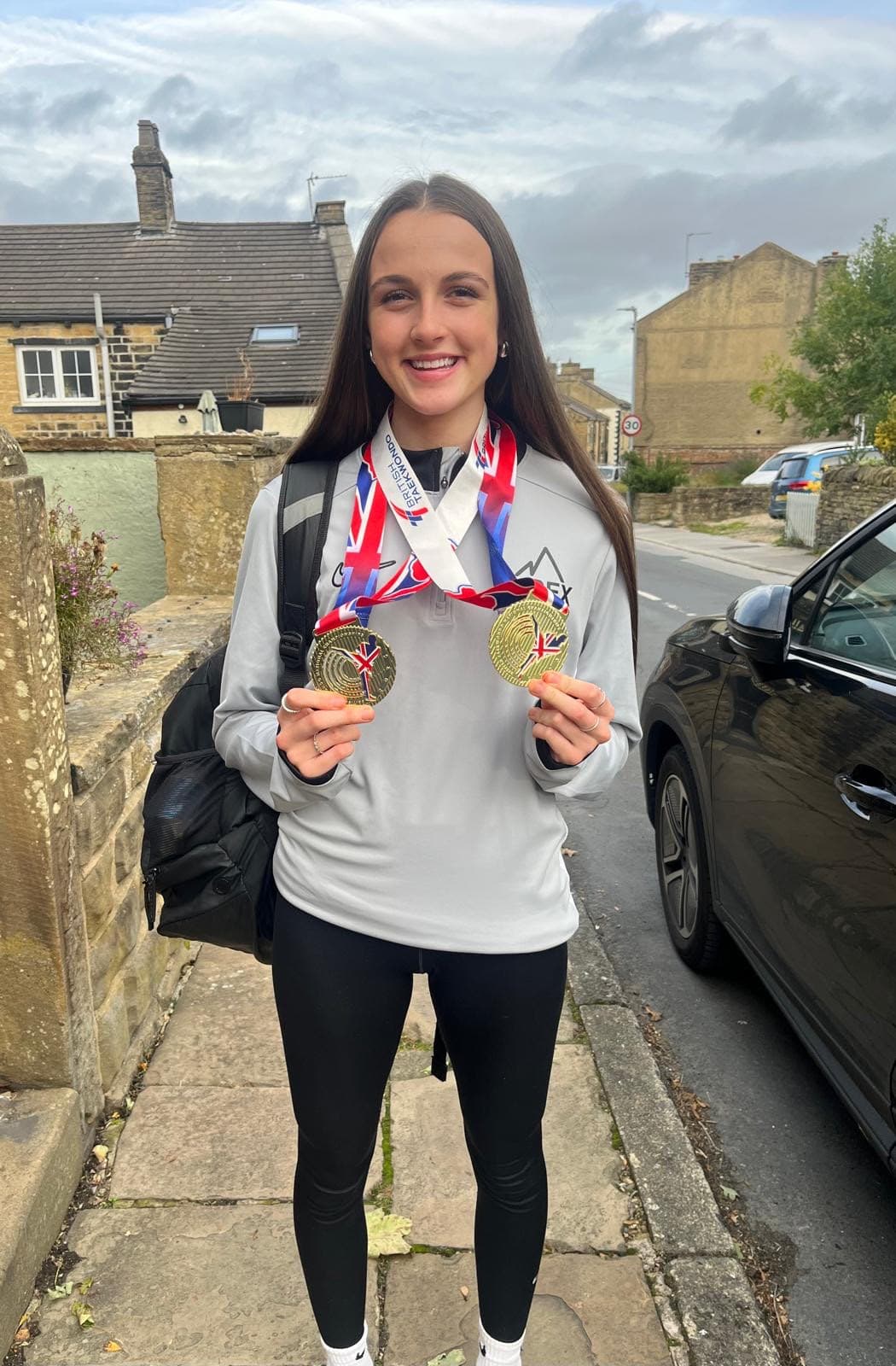 Gina Bene-Hamill holding up two gold medals