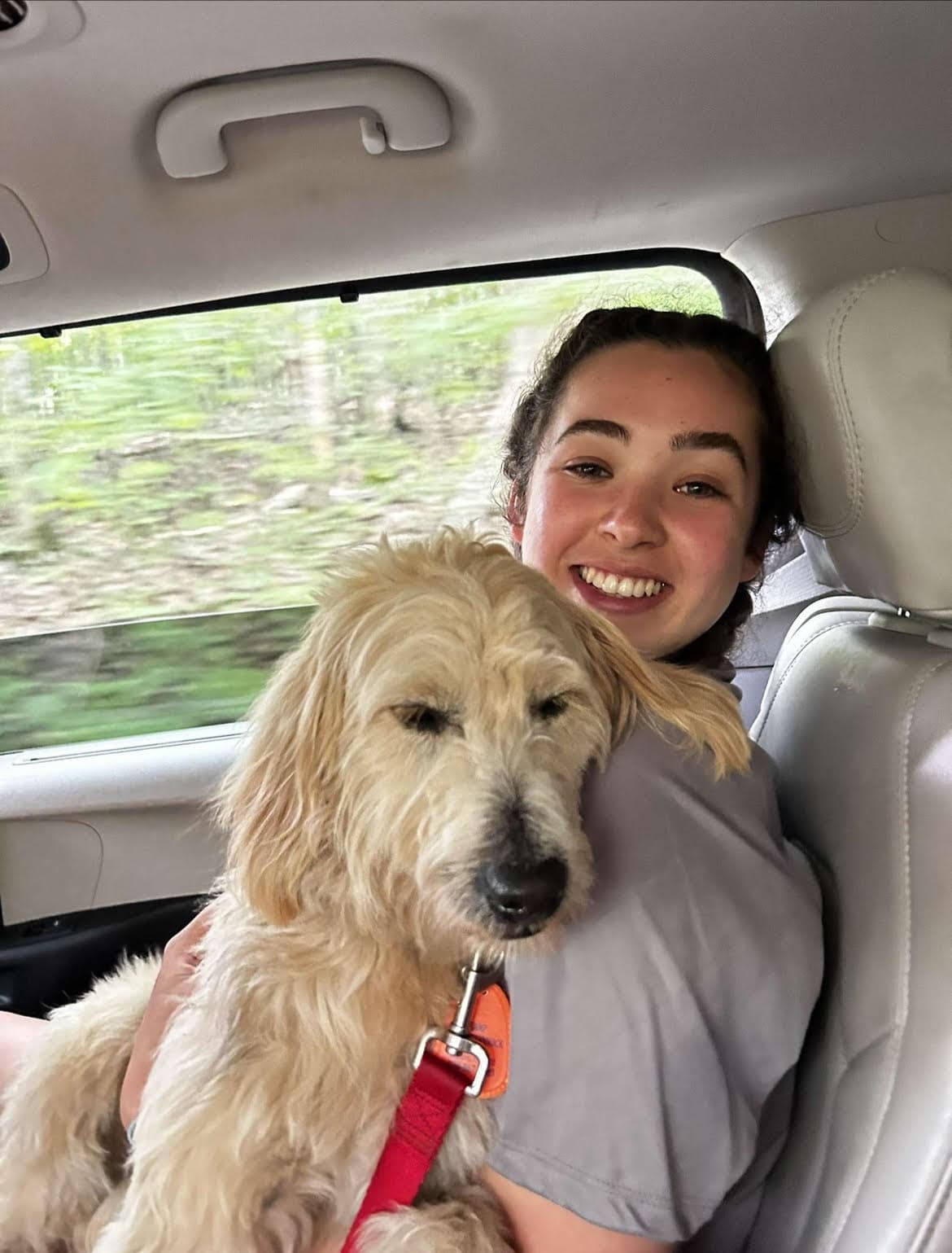 Jori Horn smiling in a car beside a goldendoodle during her first summer